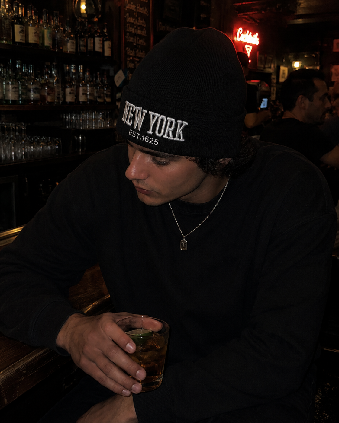 Model wearing a New York beanie at a dimly lit bar
